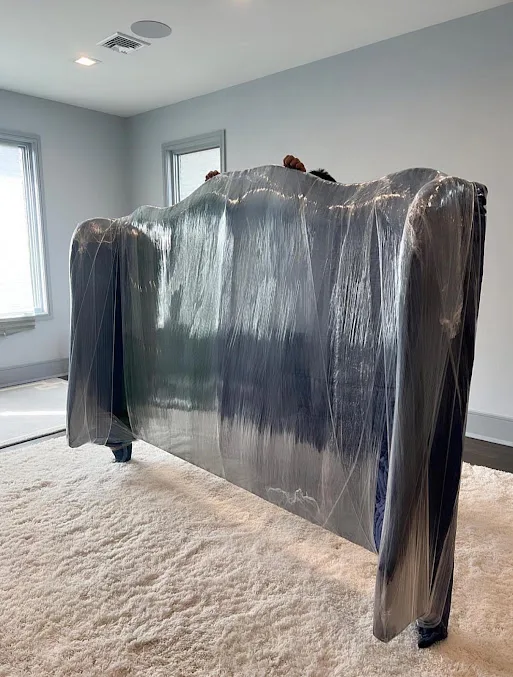 Bed headboard covered with protective padding and secured with stretch wrap