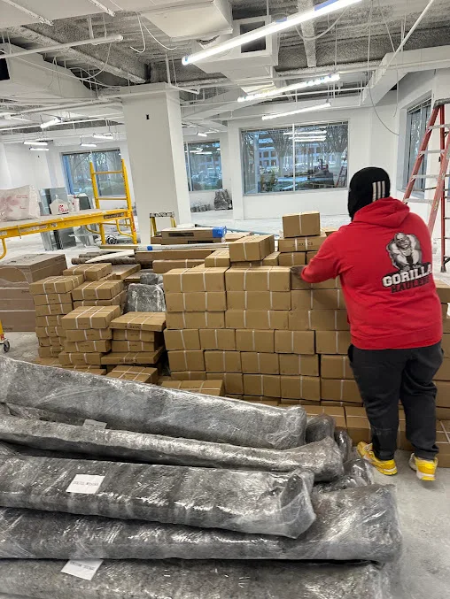 Gorilla Haulers crew member beside stacked boxes and wrapped equipment in a commercial space