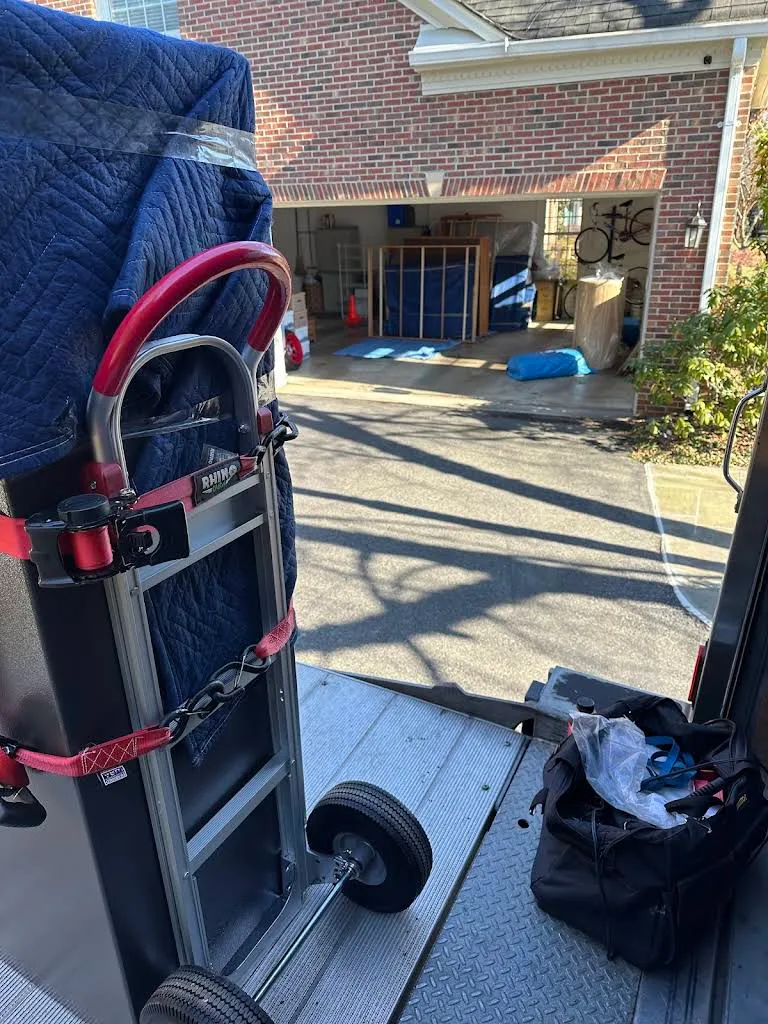 Blanket-wrapped furniture secured to a dolly on a moving truck ramp