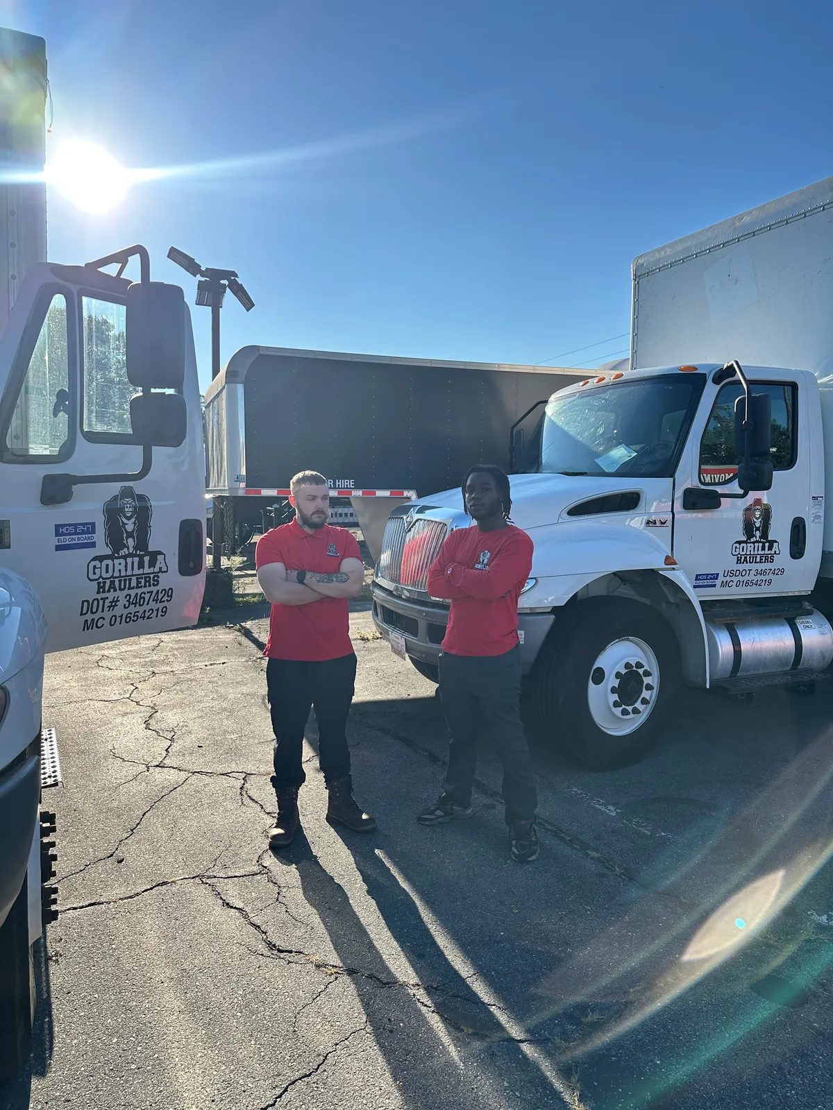 Two Gorilla Haulers movers standing between company trucks marked USDOT 3467429 and MC 01654219