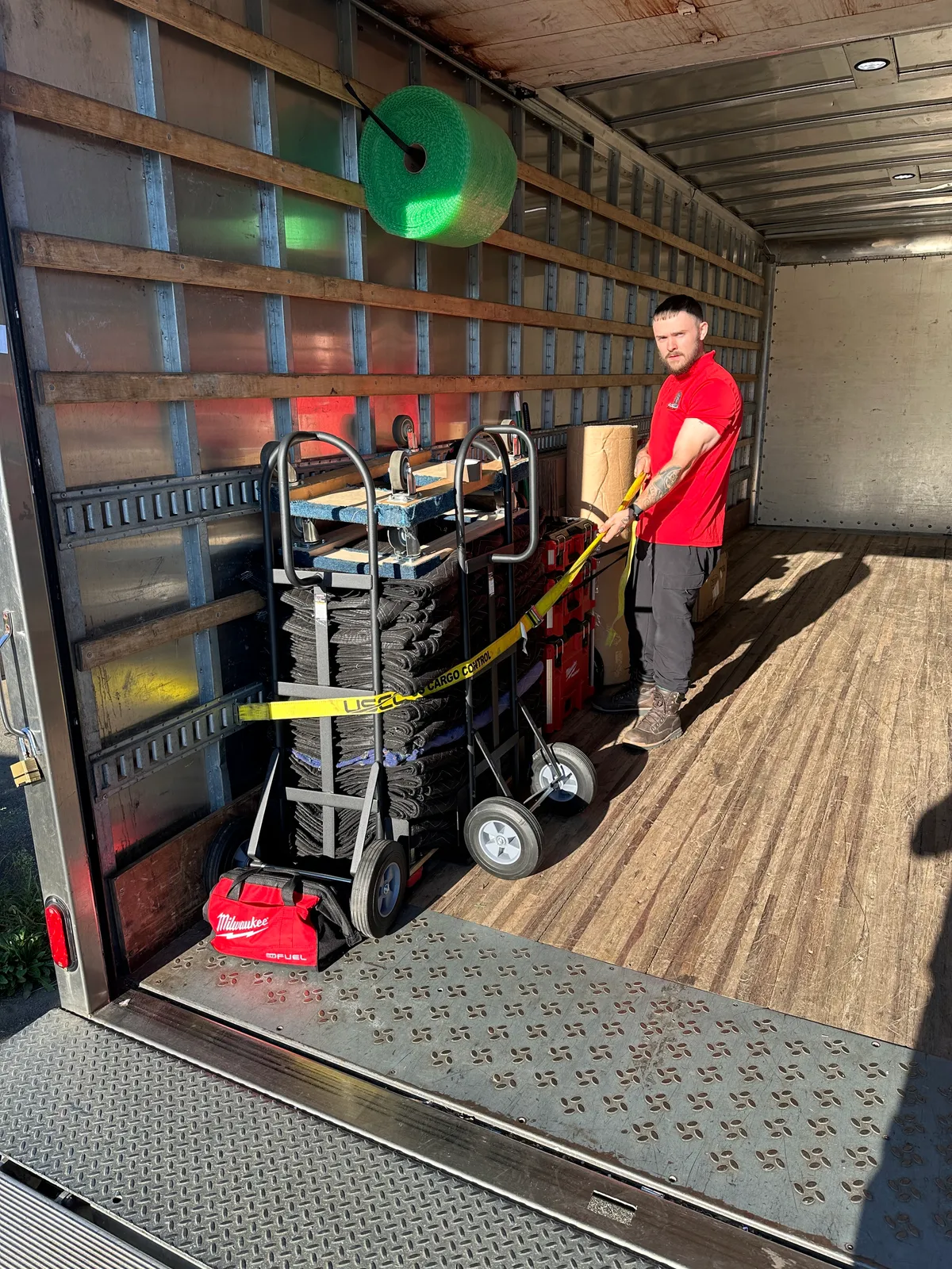Gorilla Haulers mover strapping dollies, moving blankets, and tool cases inside a truck