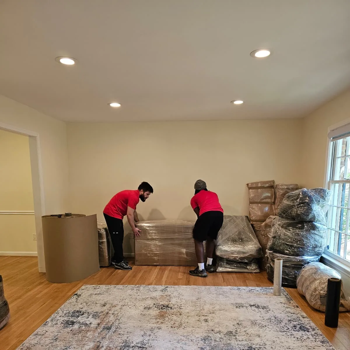 Two Gorilla Haulers movers handling wrapped furniture beside packed household items