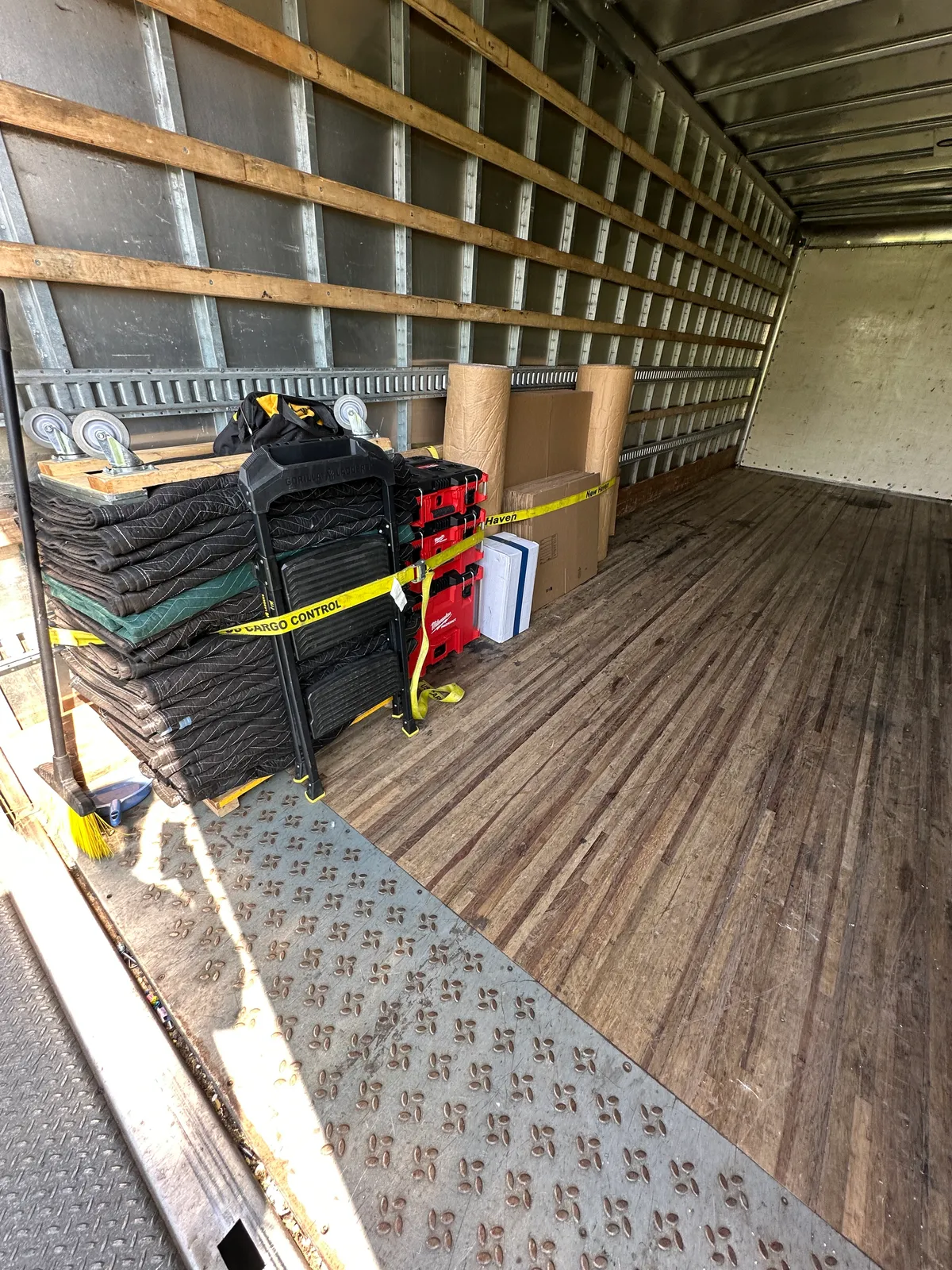 Inside a Gorilla Haulers truck: stacked moving blankets, dollies, tool cases, and packing paper strapped to the wall